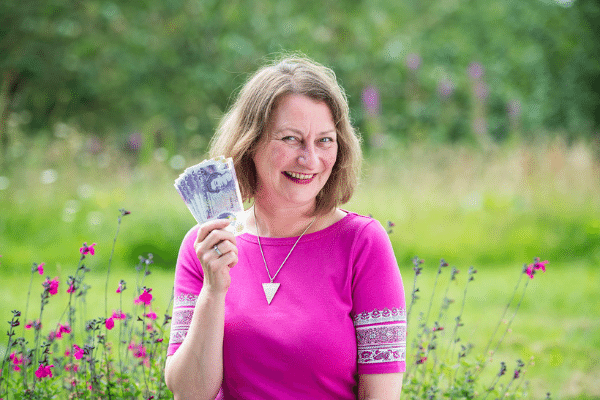 Jenny holding money, british pounds in a garden