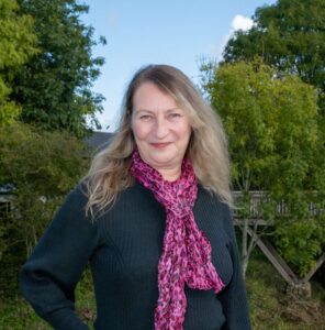 Jenny Bracelin, Shropshire Business Coach standing in nature wearing a pink scarf.